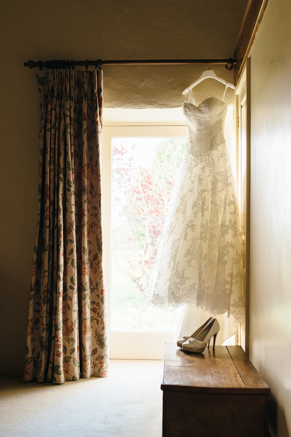 Wedding dress hung in corner by window. Caswel House Wedding Photography