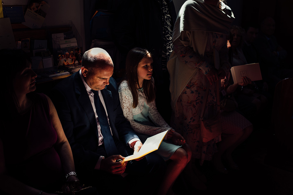 Caswel House Wedding Photography Guests sitting in darkened room, one light shining above