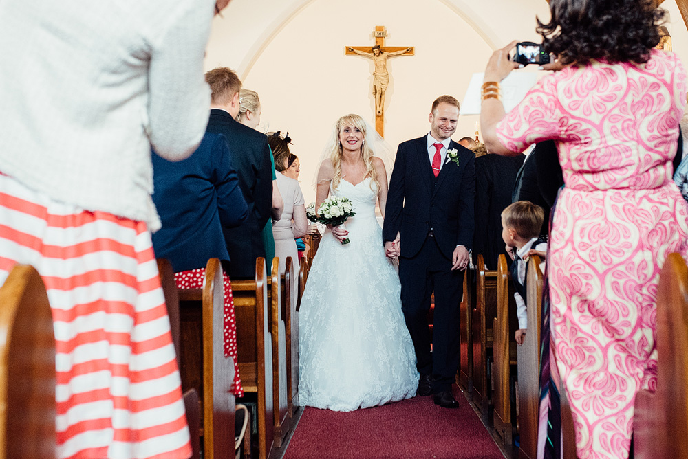 Bride and groom walking down church aisle holding hands