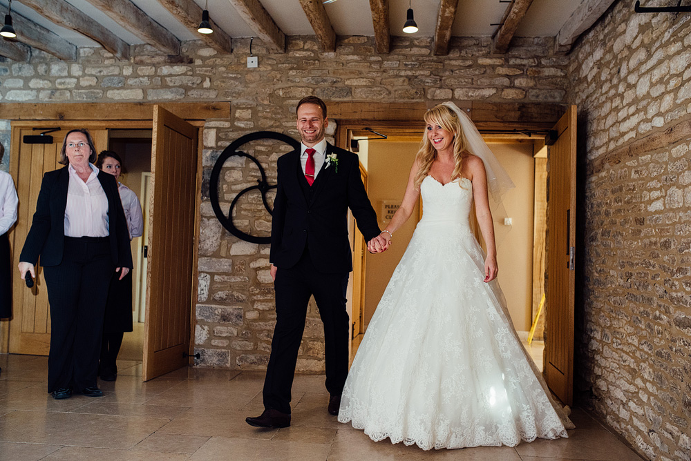 Bride and groom walking into reception hall, holding hands