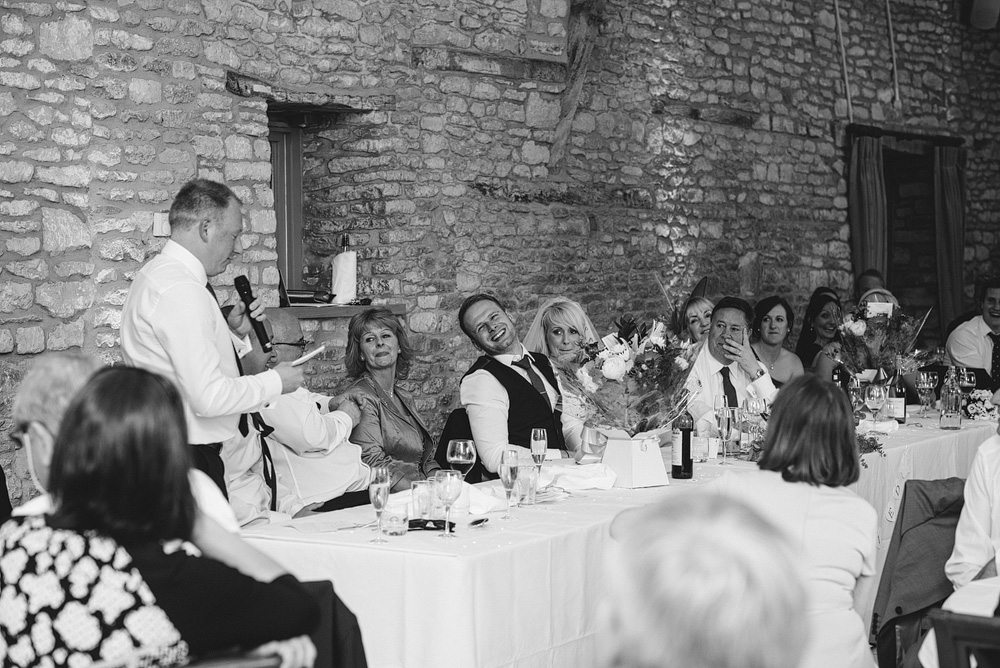 Black and white photo, guest giving speech at wedding table