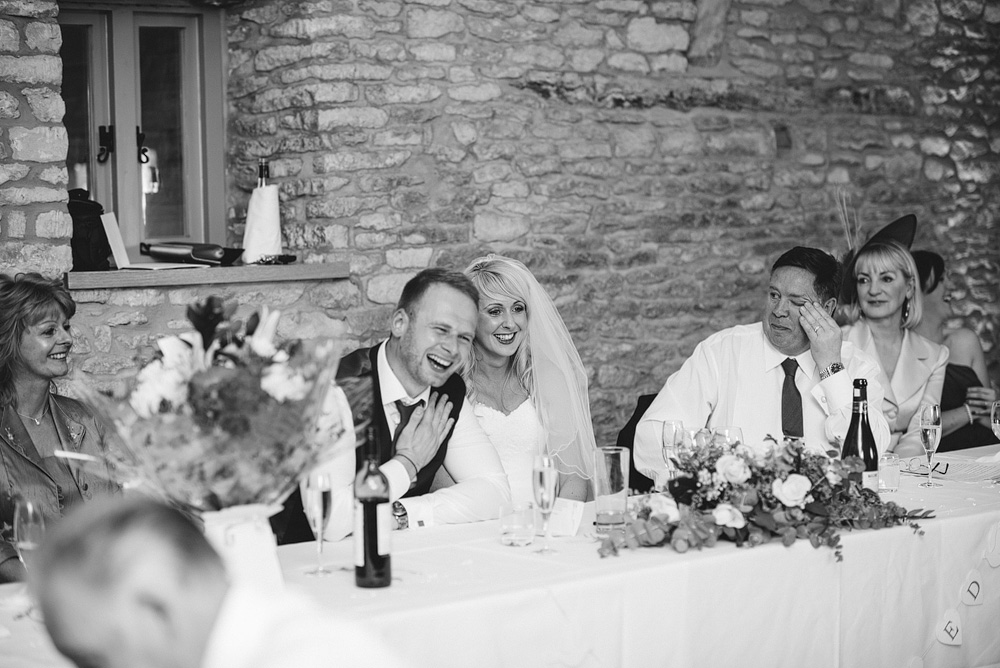 Black and white photo, bride and groom smiling and laughing at table