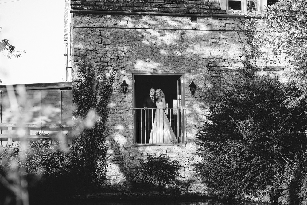 Black and white photo, bride and groom looking outside over gated window