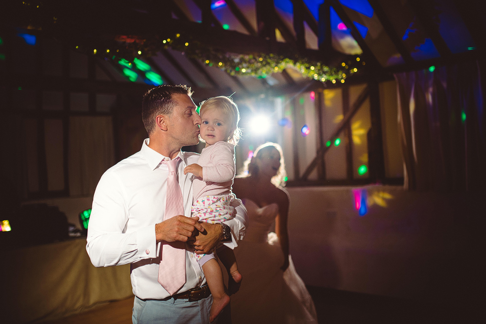 Groom holding daughter at wedding