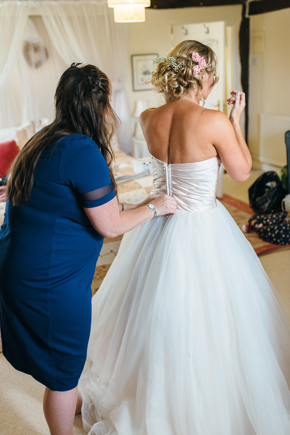 Guest helping bride get into dress