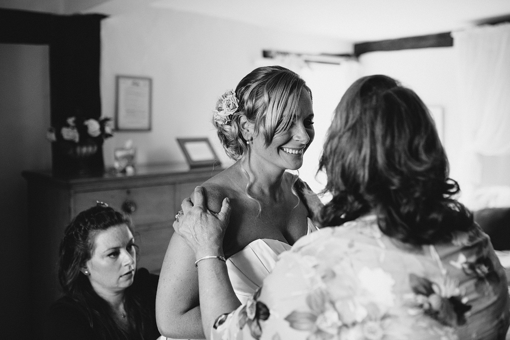 Bride smiling with guests while getting into wedding dress