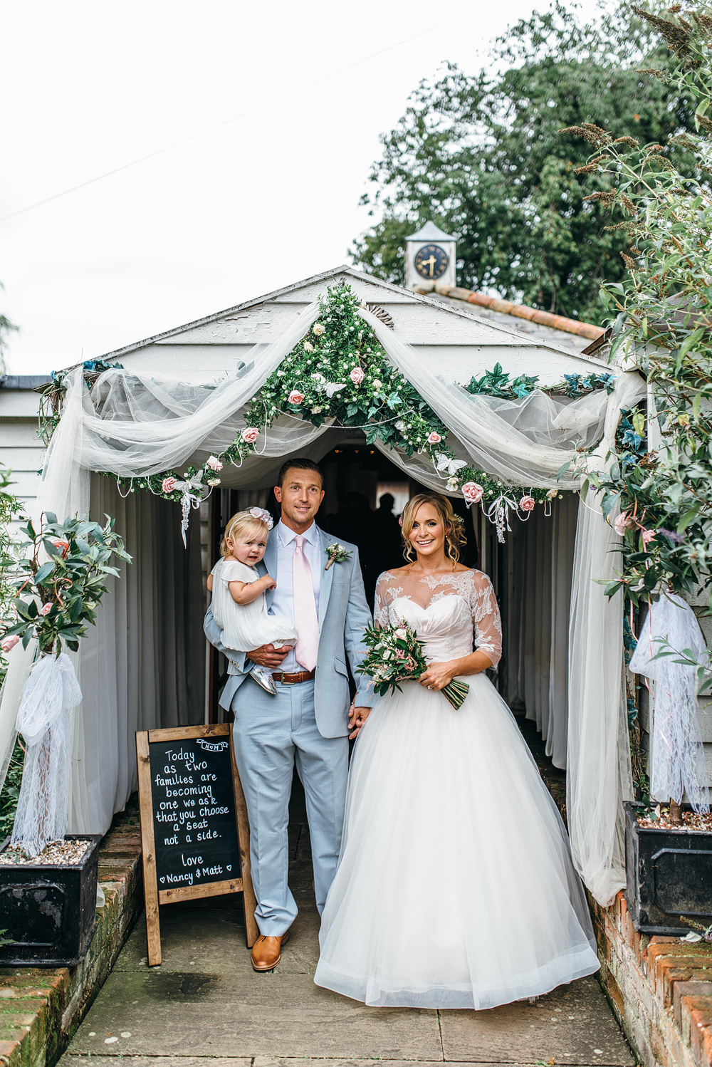 Bride and groom with child standing under canopy