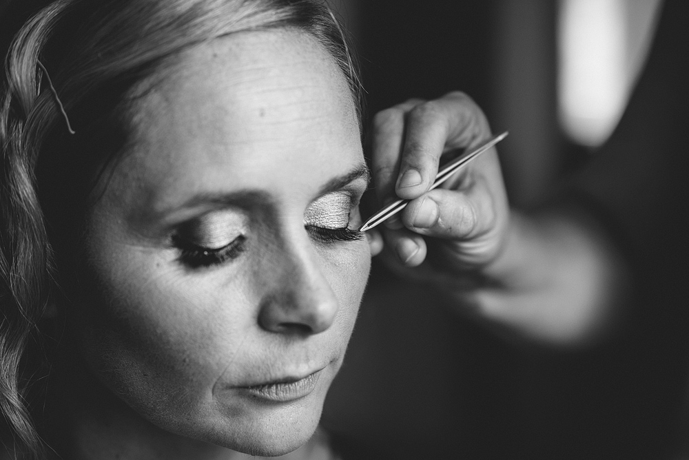 Stylist applying bride's makeup at wedding