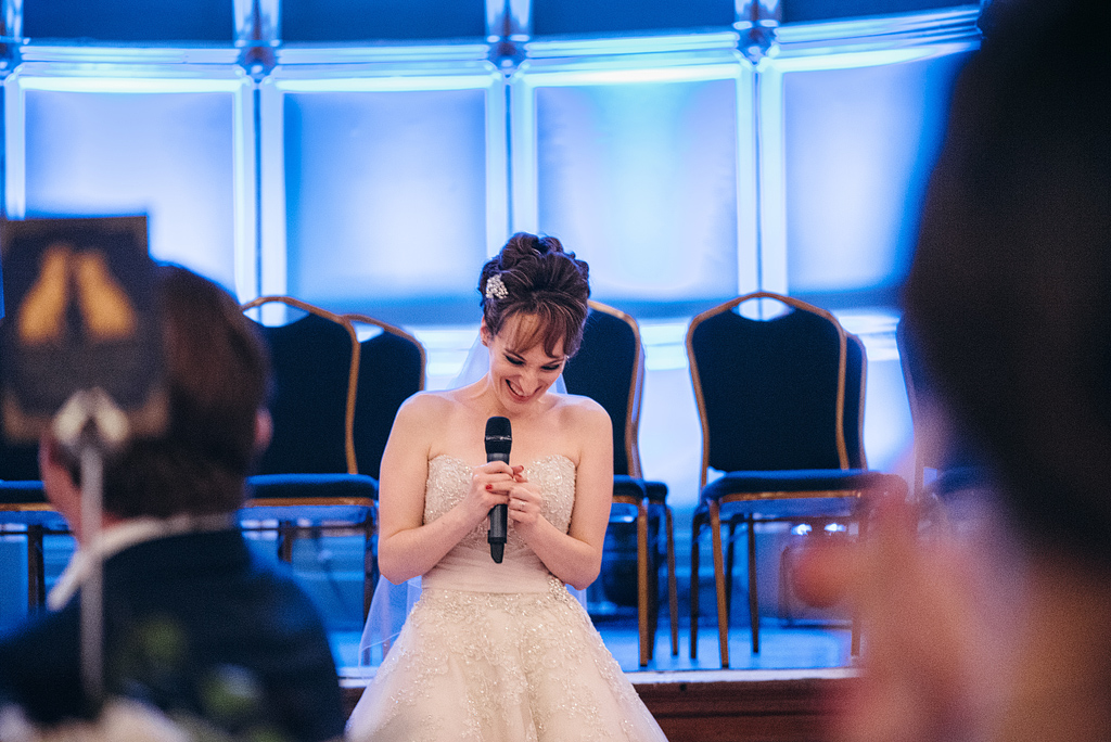 Bride smiling while giving speech at wedding reception