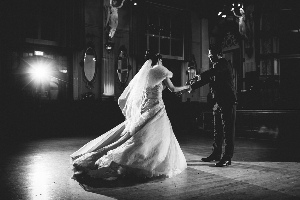 Bride and groom holding hands on dance floor together