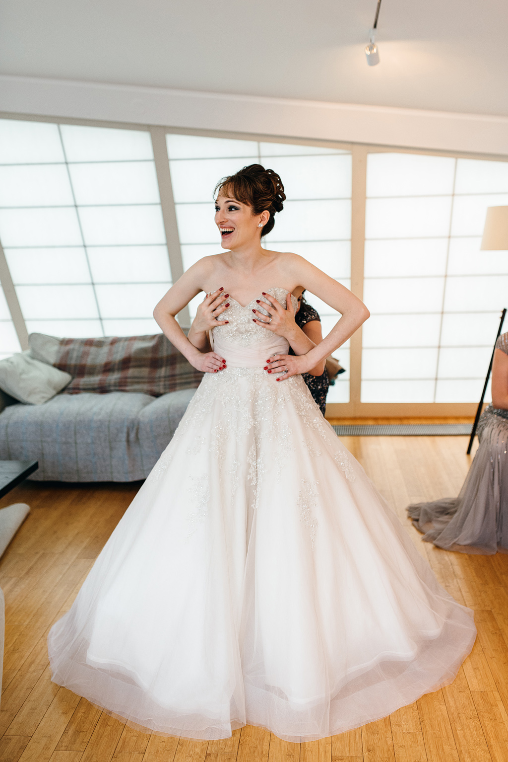 Bride laughing while getting into wedding dress