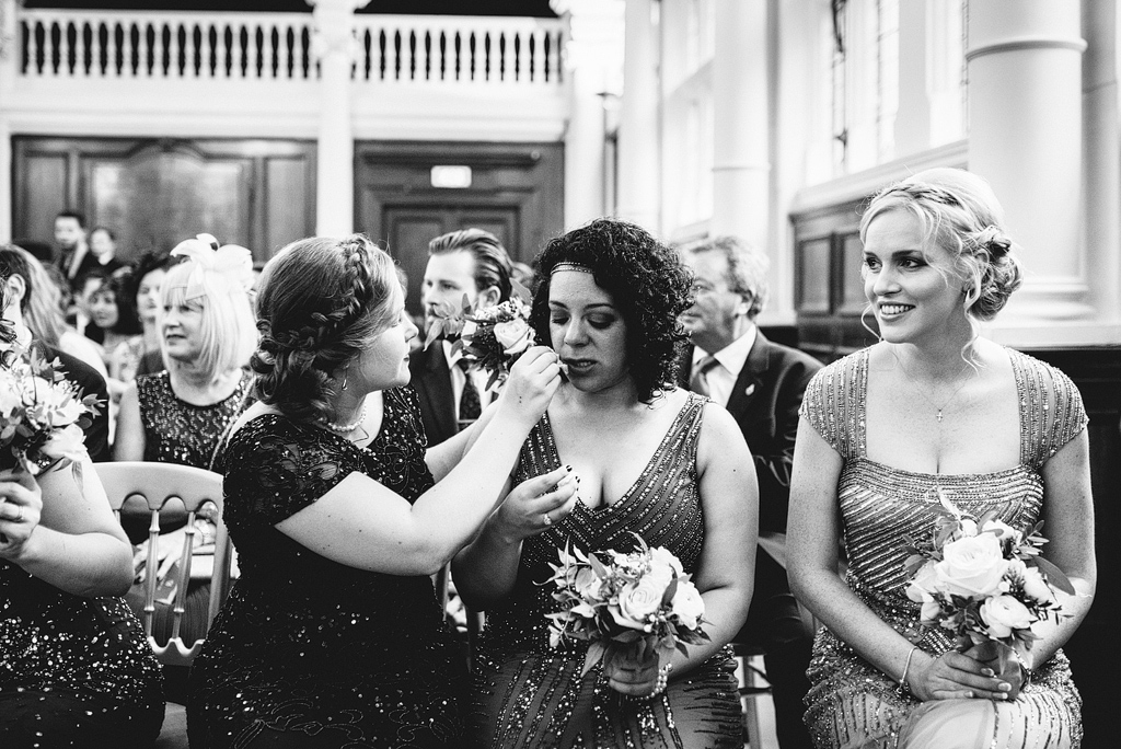 Woman helping guest with makeup at wedding ceremony