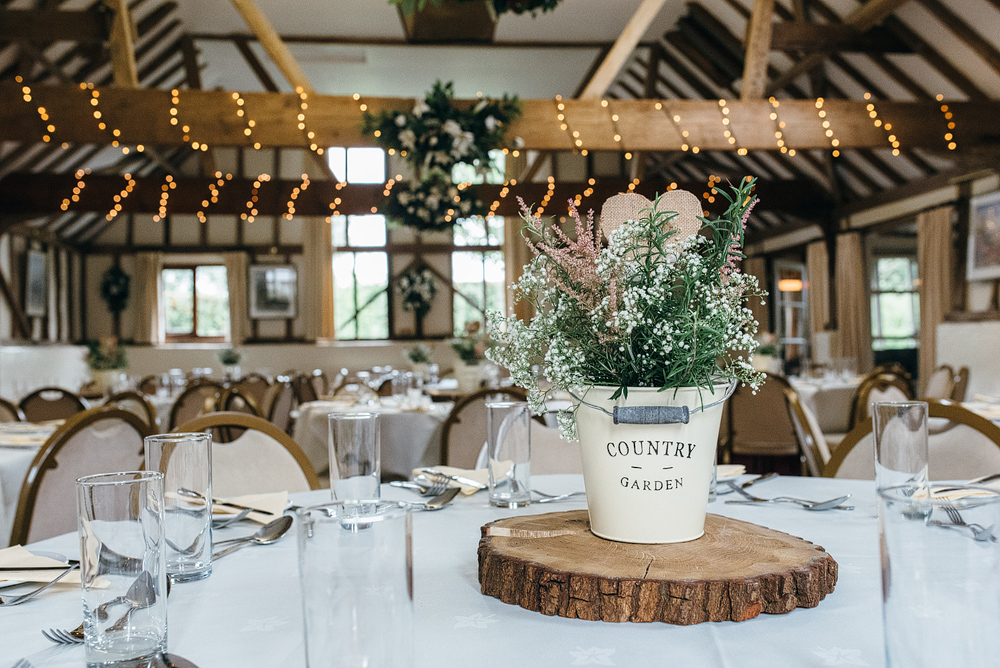 Rustic Wedding Ideas. Table flowers in bucket on log stand.