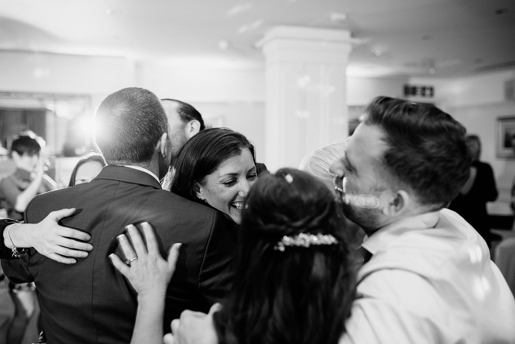 Group hug of groom with guests at wedding reception