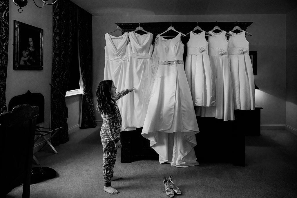 Little girl pointing to bridal party dresses hanging