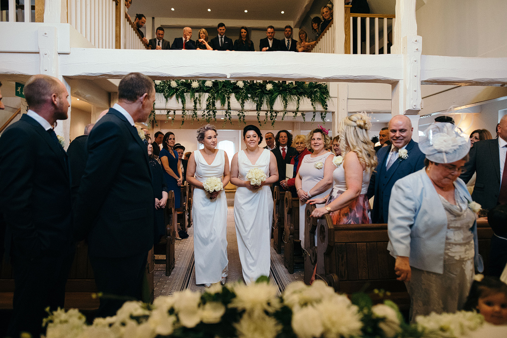 Bridesmaids walking down aisle in wedding chapel