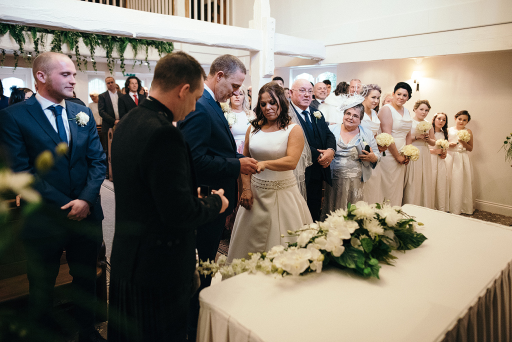 Groom placing ring on bride's finger at wedding ceremony