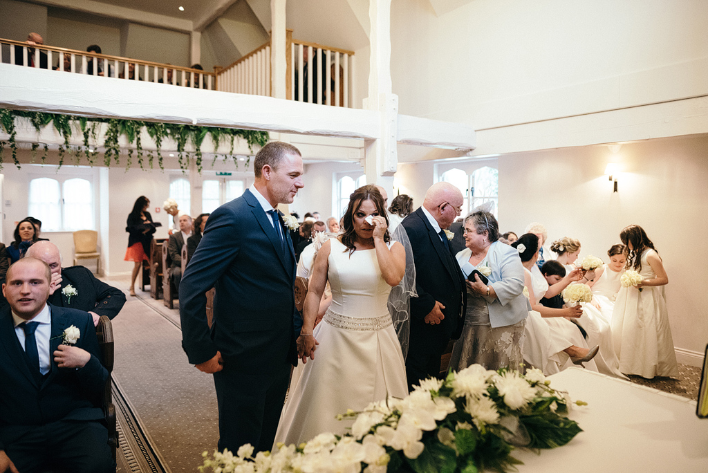 Bride wiping tears of joy at wedding ceremony