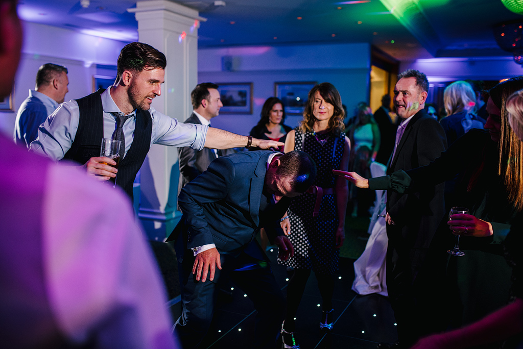 Guests playing limbo at wedding reception dance floor