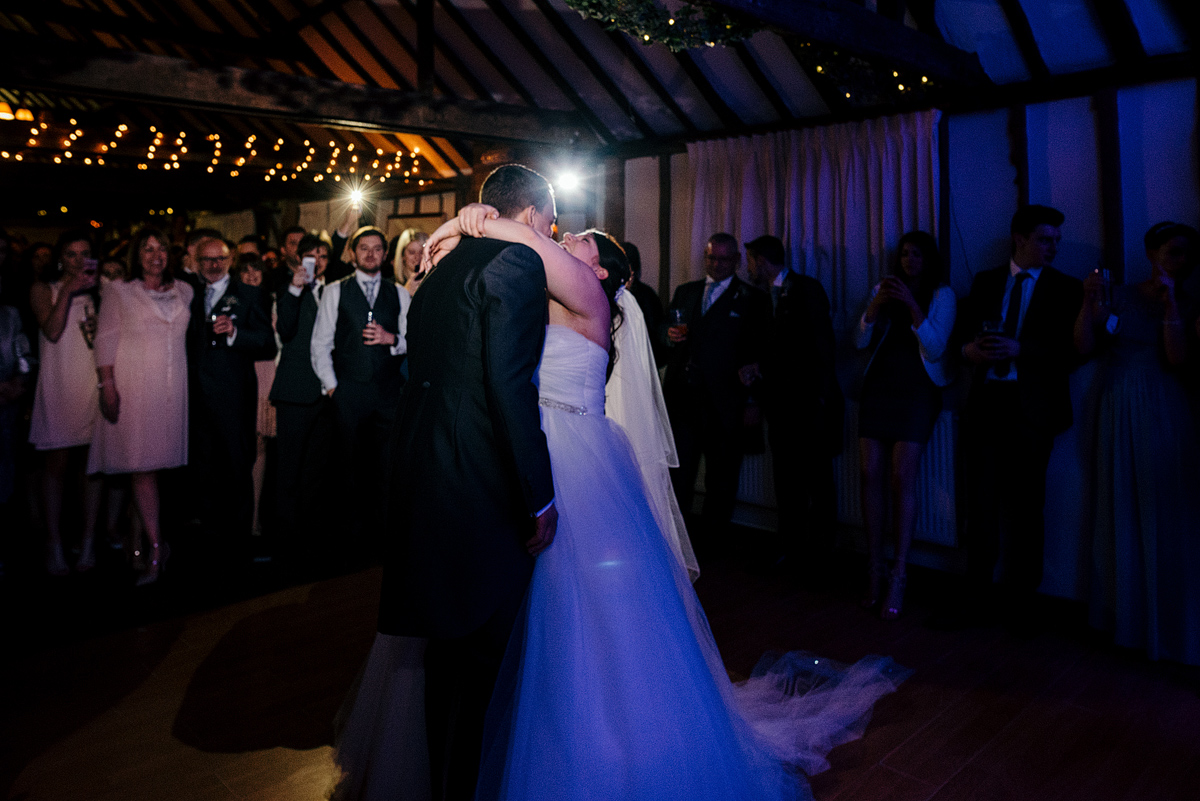 Bride and groom sharing dance together while guests watch