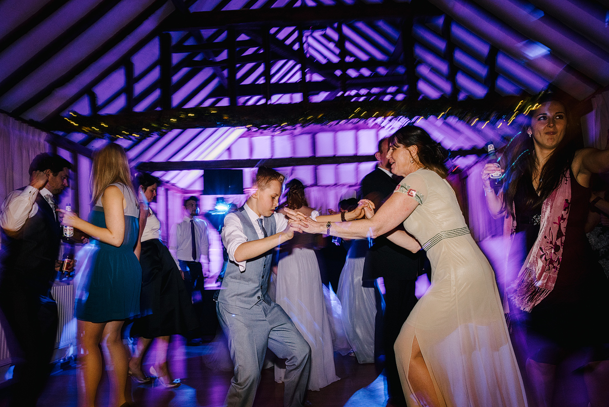 Guests dancing in barn with purple lights overhead