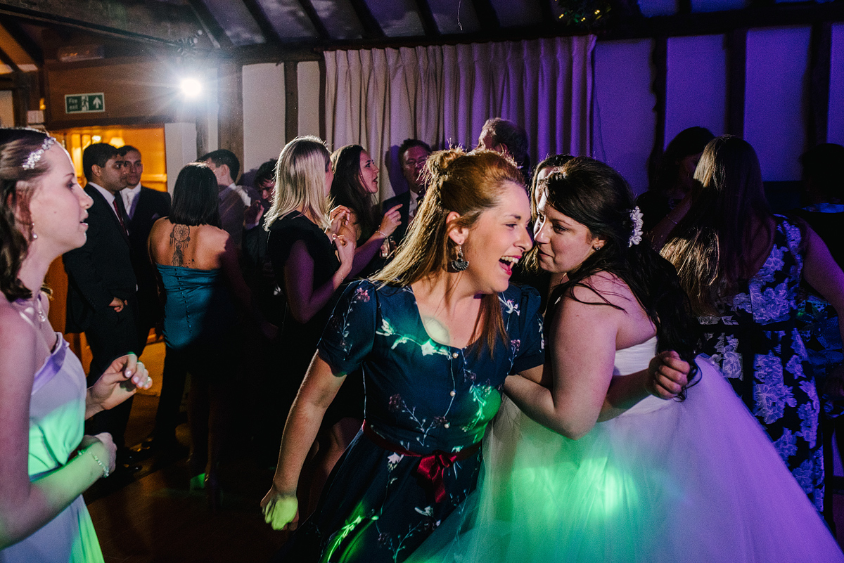 Bride and guest laughing with green and purple lights above