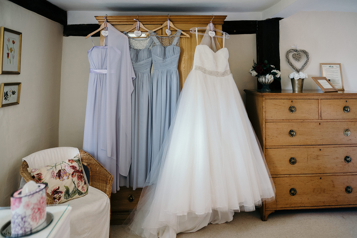Bride and bridesmaid dresses hung on dresser.