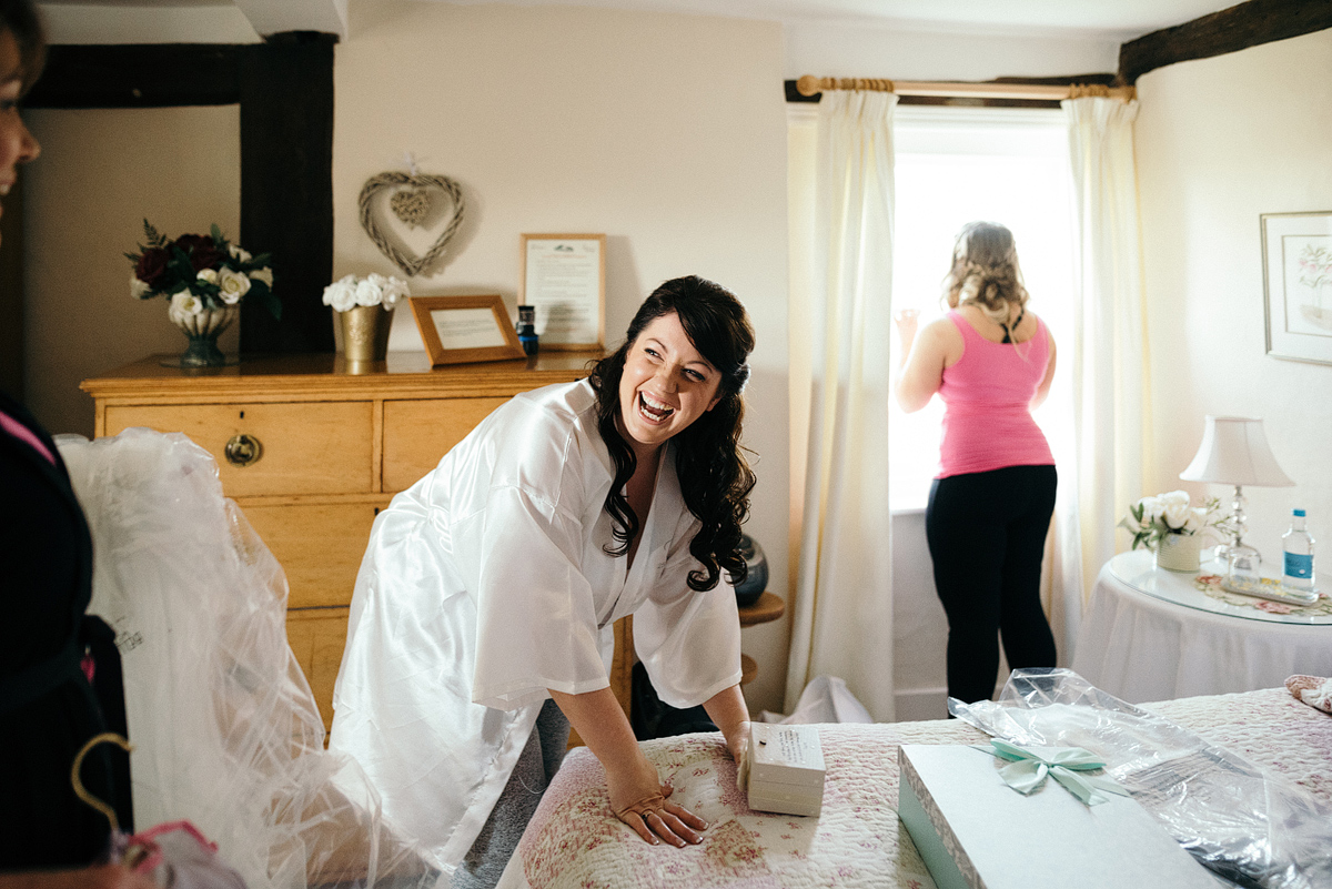 Bride laughing while another guest looks out the window.