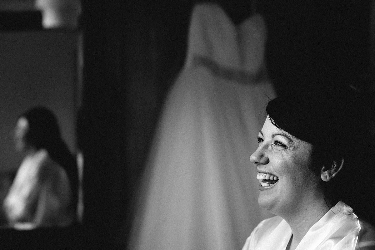 Close up of bride laughing, her reflection and dress in background.