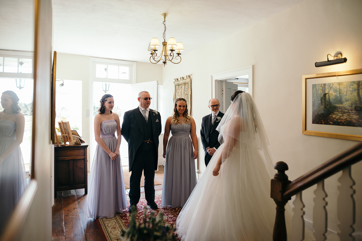 Bride standing in front of bridemaids and fathers.