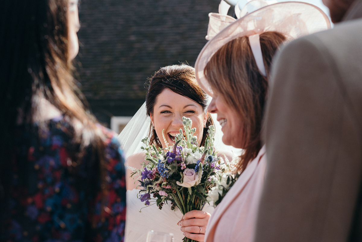Bride laughing through her bouquet outside