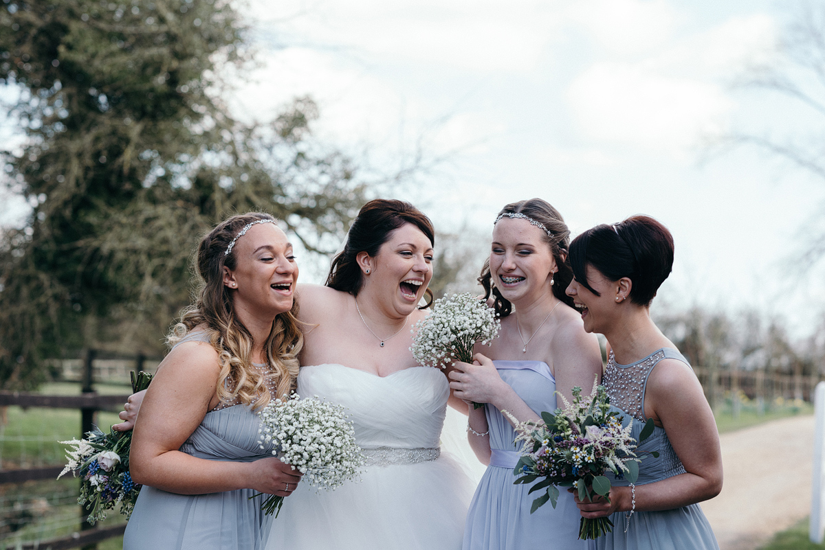 Bridesmaids and bride standing together laughing.