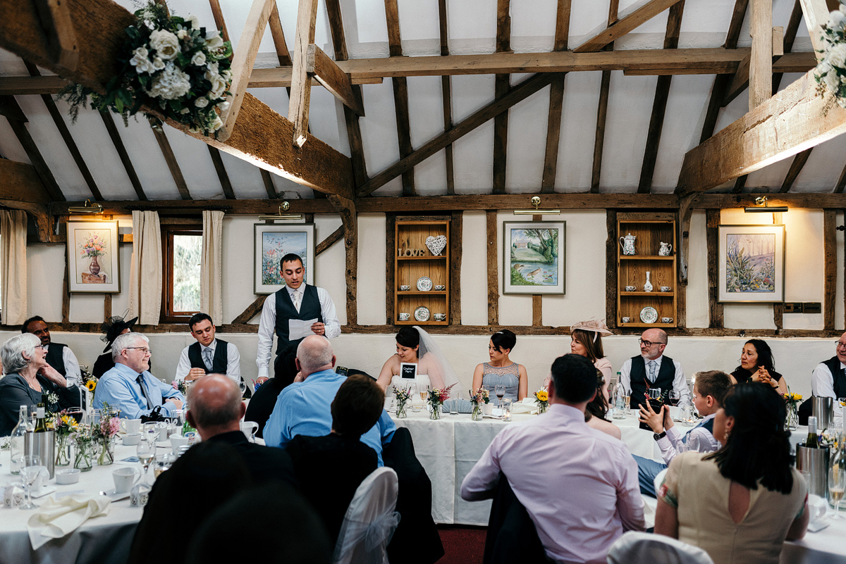 Tables of guests listening as groom makes speech