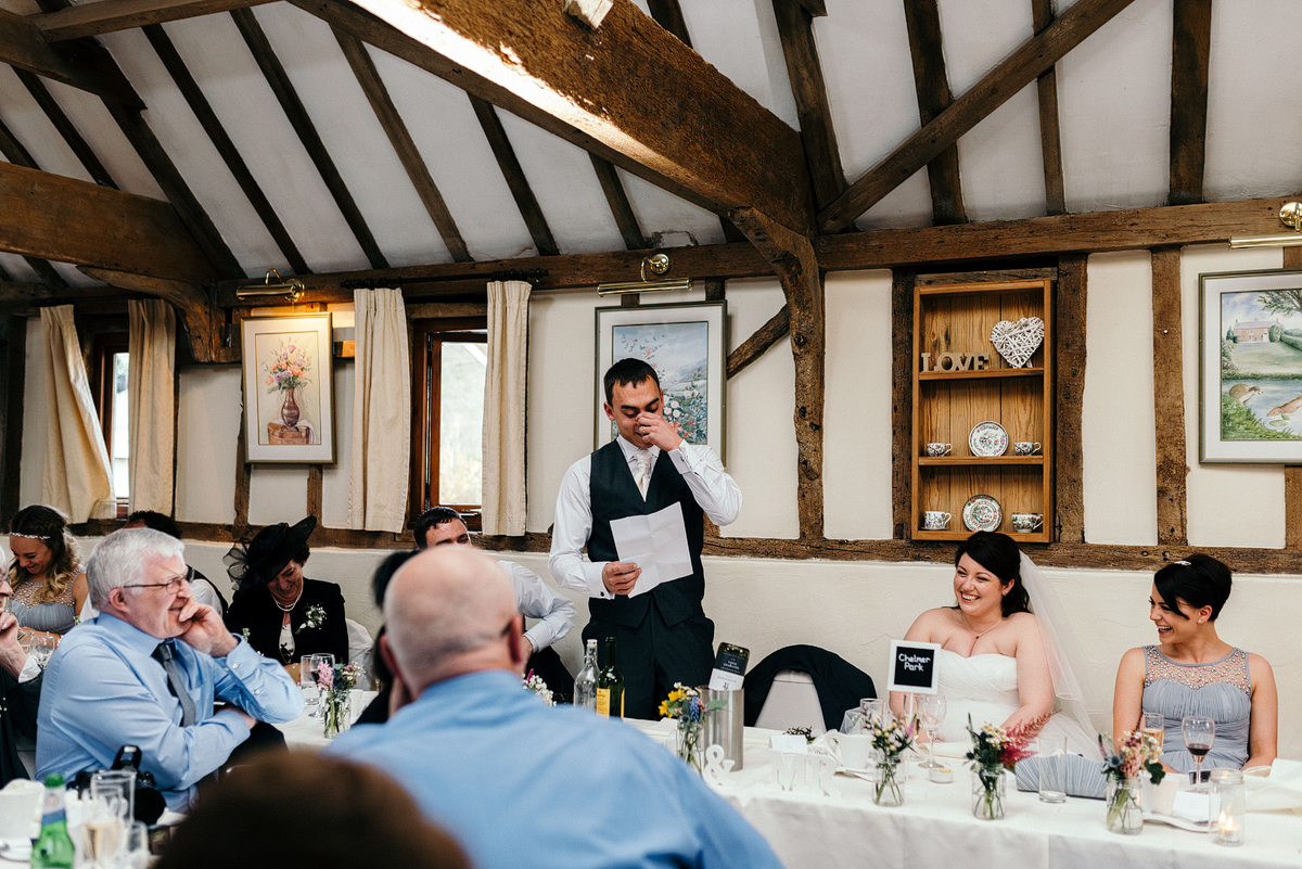 Groom reading speech while guests listen, laughing