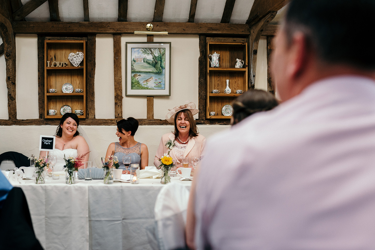 Bride and guests laughing at table.