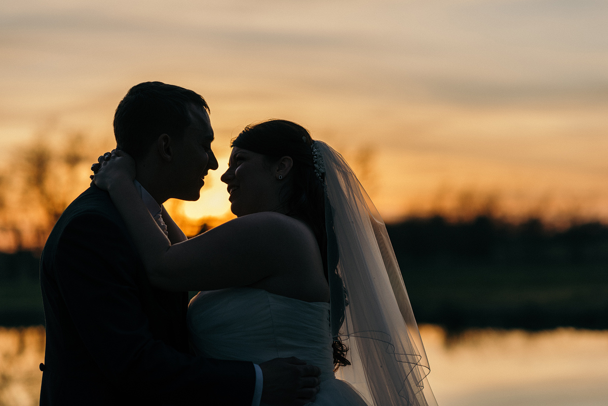 Bride and groom embrace as the sun sets.