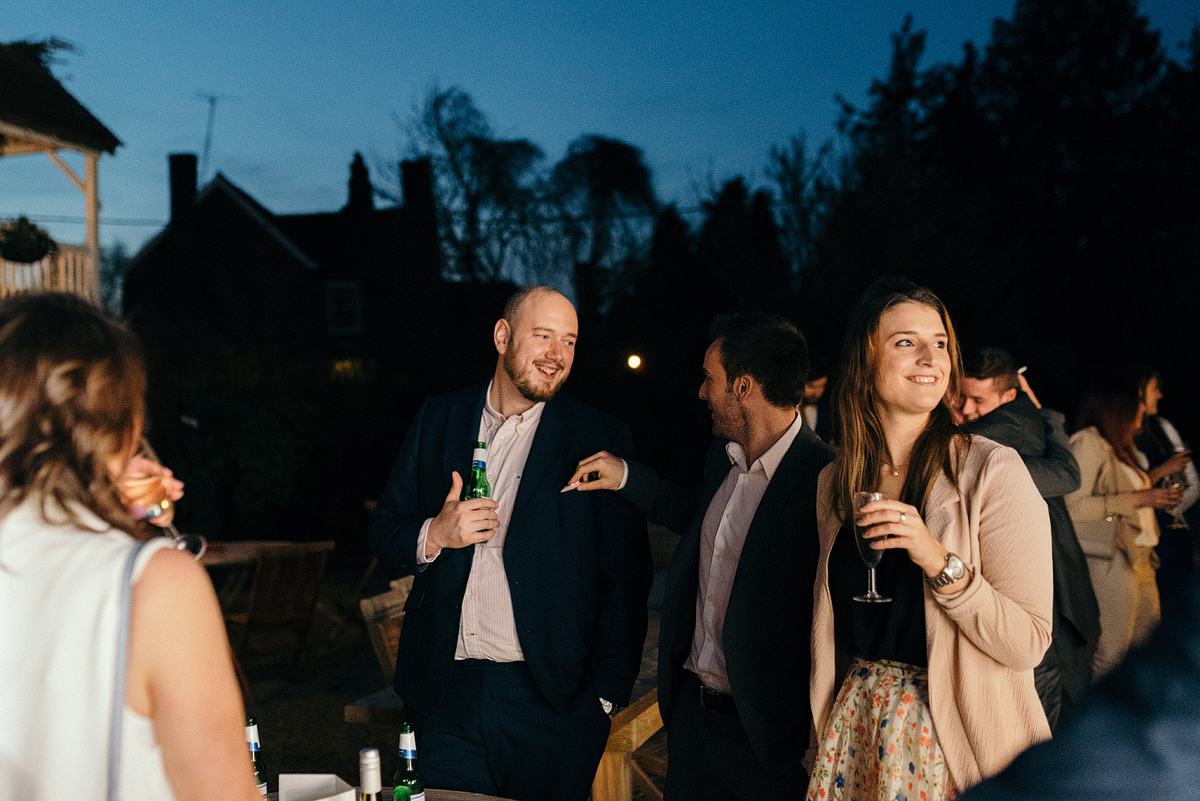 Guests smiling and talking outside while holding drinks